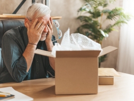 Damaged parcel box. Upset mature man closes his eyes, returns the goods to the store. A disgruntled online shopper. Broken item, delivery problem.