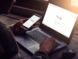 Man using both his laptop and mobile phone with Google on display.